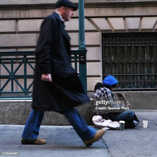 Homeless man sits along Wall Street during the beginning of the Christmas holiday week on December 23, 2019 in New York City. Following news that...