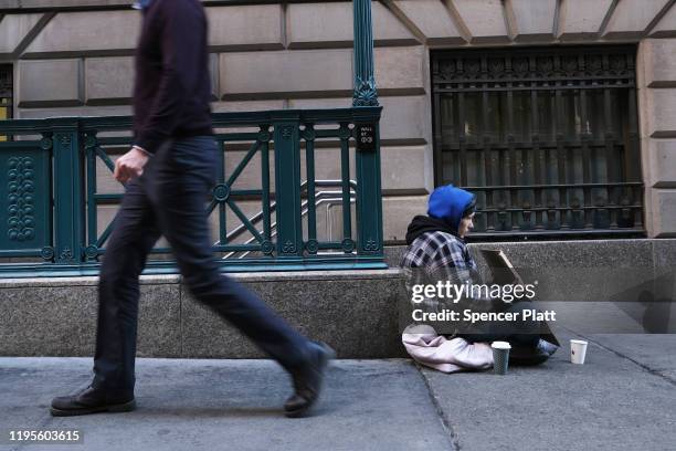 Homeless man sits along Wall Street during the beginning of the Christmas holiday week on December 23, 2019 in New York City. Following news that...