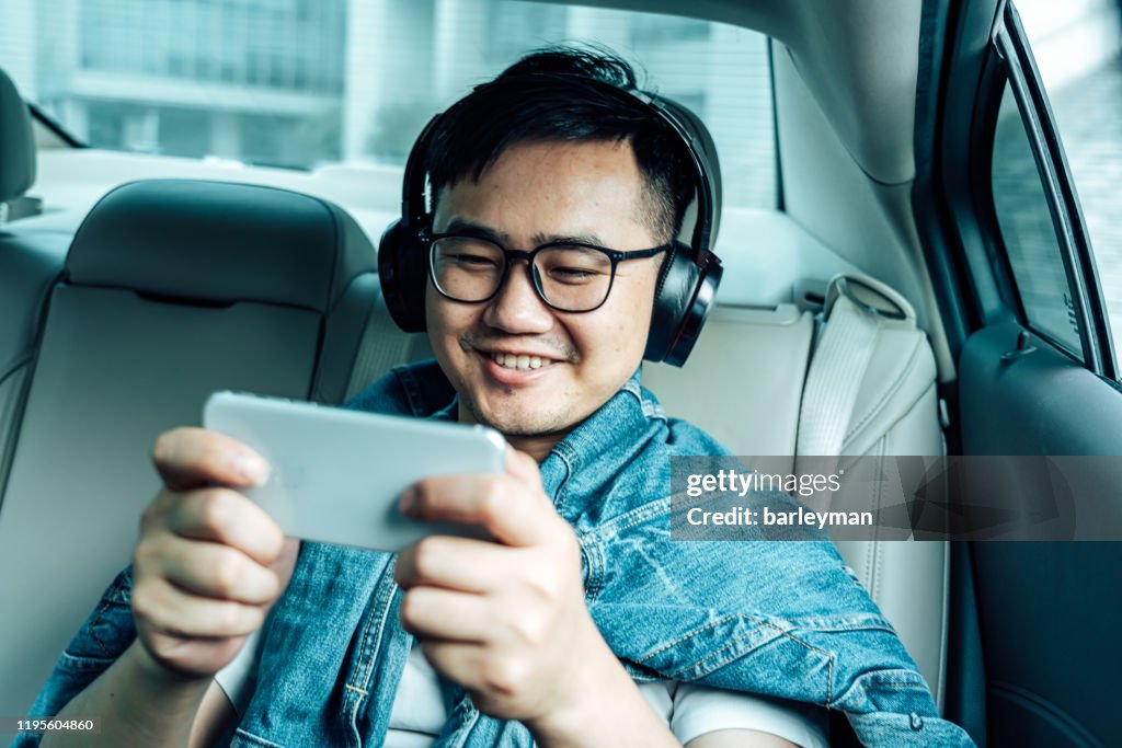 A young male play mobile game  in the car