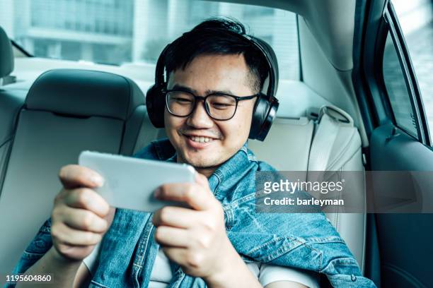 a young male play mobile game  in the car - chinese music imagens e fotografias de stock