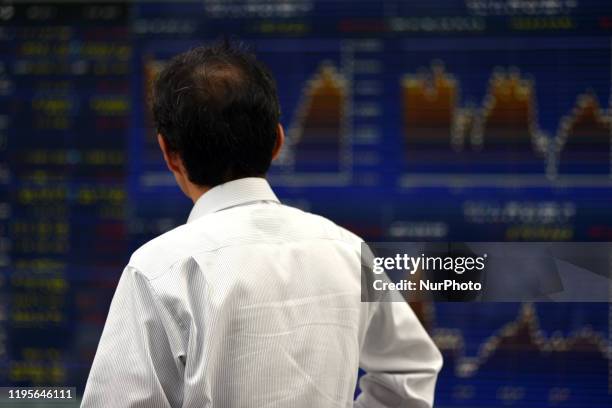 Man is reflected in an electronic display showing world markets indices and exchange rates of the Japanese yen against world currencies outside a...