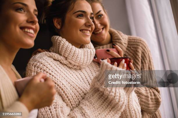 vista ad angolo basso di tre donne felici che guardano attraverso la finestra - maglione foto e immagini stock