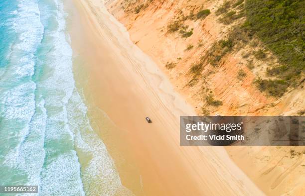 aerial view of sand dunes with vehicles travelling along the sand and the ocean - rainbow beach stockfoto's en -beelden