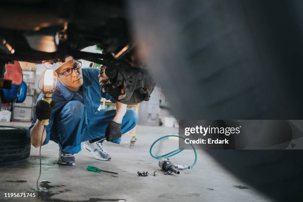 thai mechanic man with lamp working at car auto repair  shop stock photo - car inspection stock pictures, royalty-free photos & images