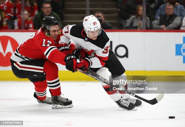 Pavel Zacha of the New Jersey Devils is pressured while advancing the puck by Dylan Strome of the Chicago Blackhawks at the United Center on December...