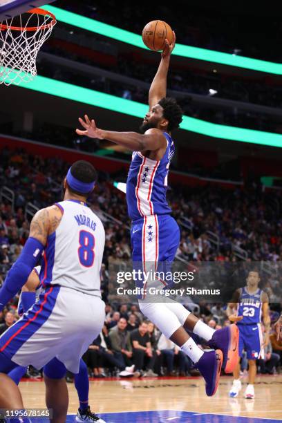 Joel Embiid of the Philadelphia 76ers dunks past Markieff Morris of the Detroit Pistons during the second half at Little Caesars Arena on December...