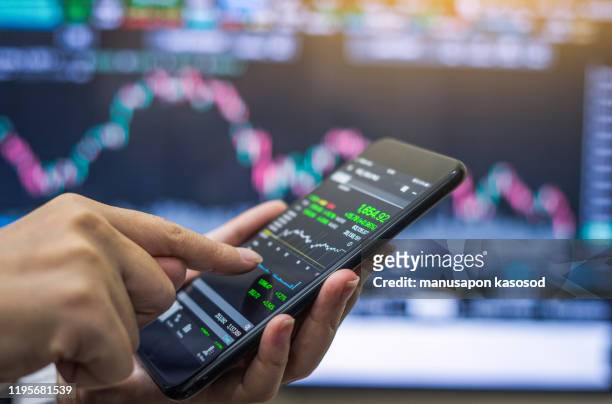 businessman checking stock market on mobile phone,stock market - trading resumes at the stock exchange of thailand stockfoto's en -beelden