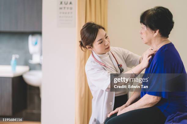 eine asiatische chinesische ärztin, die eine asiatische chinesische seniorin im beratungsraum der klinik untersucht - chinese medicine stock-fotos und bilder