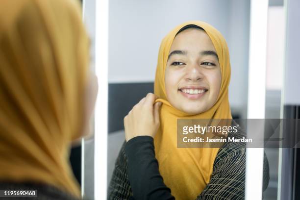 young woman with hijab looking at herself in the mirror - beautiful arabian girls stock pictures, royalty-free photos & images