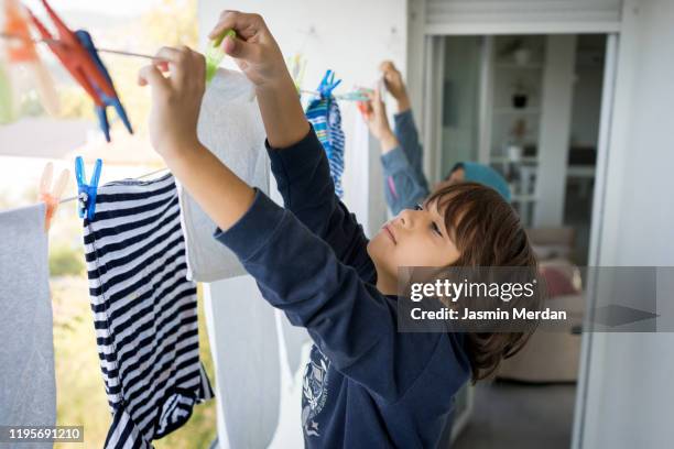 child hanging clothes on clothesline - clothesline stockfoto's en -beelden