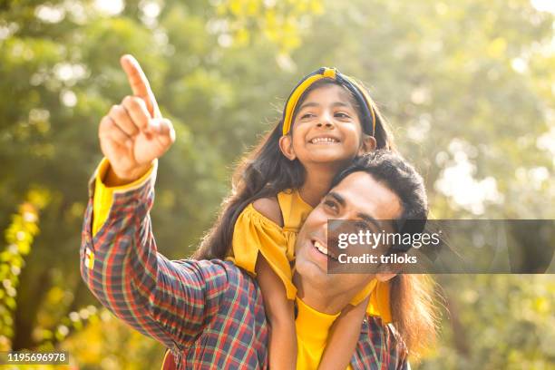 vater und tochter genießen huckepack-fahrt - indian girl pointing stock-fotos und bilder