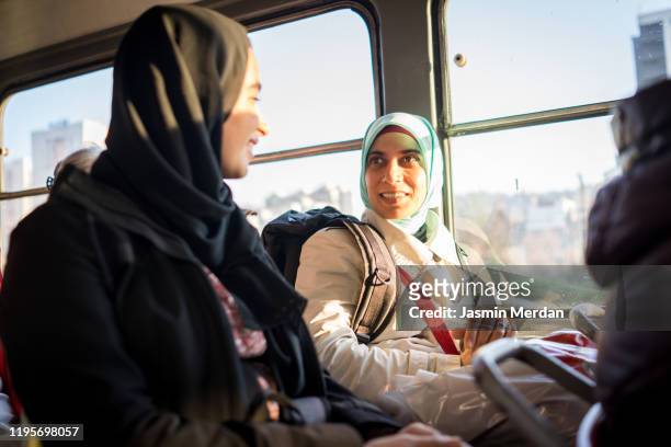 two middle eastern females riding in public transportation - business or women or family or travel stock-fotos und bilder