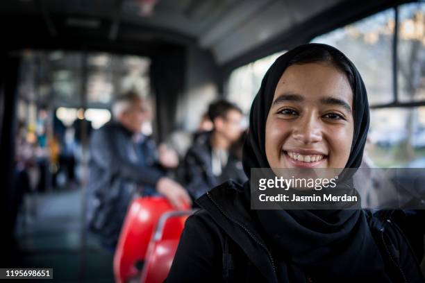 portrait of middle eastern smiling girl in tram - hijab girl stock-fotos und bilder