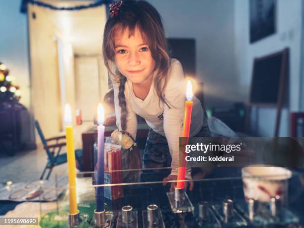 little girl lighting menorah at home - menorah fotografías e imágenes de stock