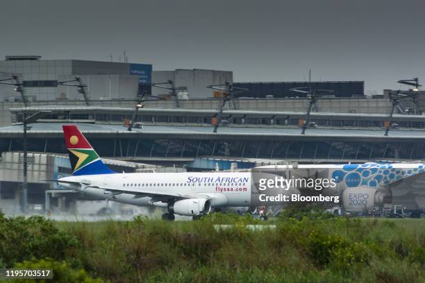 An Airbus A320 passenger jet, operated by South African Airlines , taxis past an Emirates Airline aircraft with 'Expo 2020' livery at O.R. Tambo...