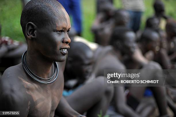 South Sudanese man looks at members of his tribe, the Mundari ethnic group, wrestle in a dusty patch where the tribe brought cattle and sheep for...