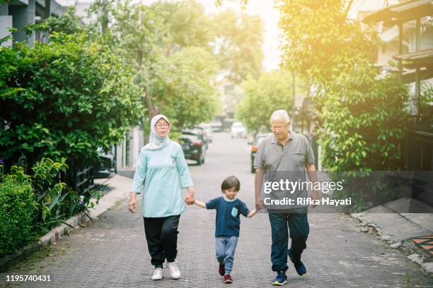 lovely senior couple walking with grandson - malay couple stock pictures, royalty-free photos & images