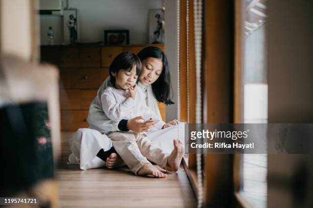 brother and sister playing mobile phone together - indonesia family imagens e fotografias de stock