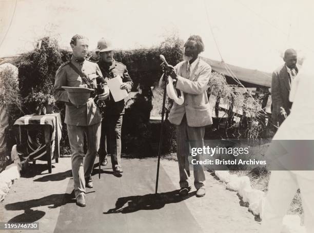 ZimbabweSouthern Rhodesia, An African man, dressed in a Western-style suit, adjusts a long staff at the entrance to a Presentation of Address for the...