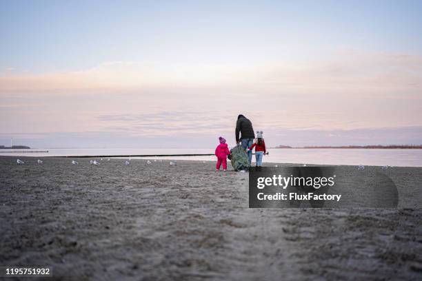 single father with two daughters dragging a christmas tree across the beach - stralsund stock pictures, royalty-free photos & images