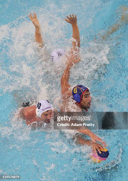 Peter Biros and Marc Minguell Alferez of Spain stretch for the ball in the Men's Water Polo first preliminary round match between Hungary and Spain...