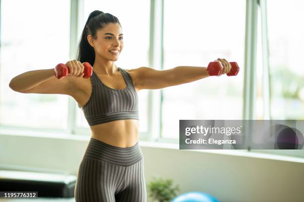 sporty beautiful woman exercising at home to stay fit - alluring fitness stock pictures, royalty-free photos & images