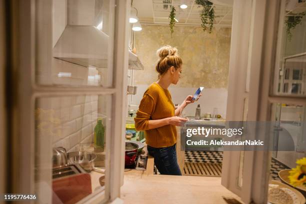 online recept controleren - woman drinking phone kitchen stockfoto's en -beelden