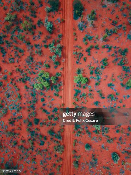 an aerial shot of a car driving on the red centre roads in the australian outback - outback queensland stock-fotos und bilder