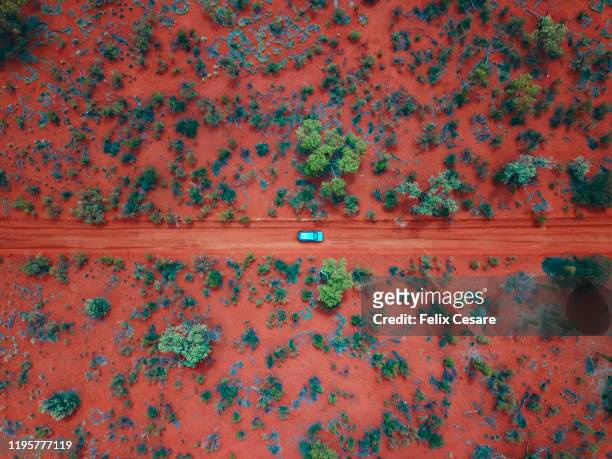 an aerial shot of a car driving on the red centre roads in the australian outback - australian desert bildbanksfoton och bilder