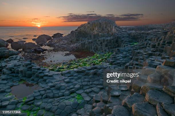 sunset over basalt columns giant's causeway, county antrim, northern ireland - giants causeway stock pictures, royalty-free photos & images