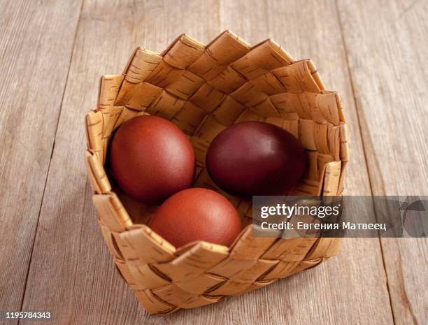 red colored spring easter eggs in a basket from bast on natural wooden background - russia celebrates orthodox easter stock-fotos und bilder