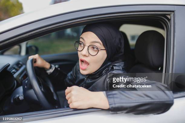 muslim woman driving a car. a puzzled expression - islamic action front stock pictures, royalty-free photos & images