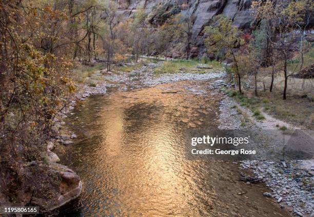 The steep rock formations and canyon walls are viewed from the Virgin River flowing through the valley floor on November 6, 2019 in Zion National...