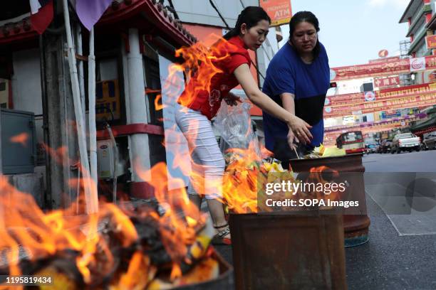 Women burn paper gold and fake money during the celebration in Chinatown, Bangkok. The Lunar New Year, also known as Spring Festival in China marks...