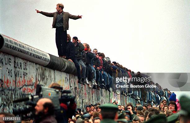People stand on a section of the Berlin Wall at Potsdamer Platz.