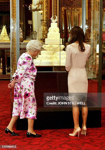 Britain's Queen Elizabeth II and Catherine, the Duchess of Cambridge view a glass cabinet containing the royal wedding cake made for her marriage to...