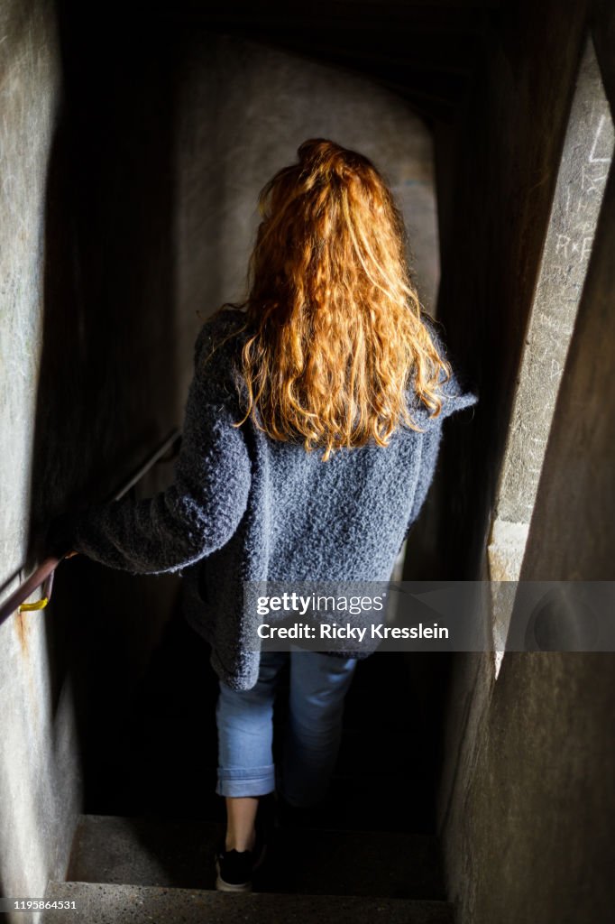 Red-Haired Girl Going Down Ancient Spiral Staircase