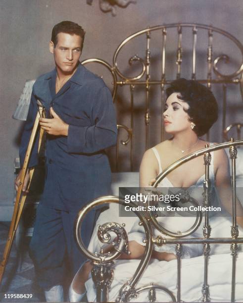 Paul Newman , US actor, wearing a blue dressing gown and holding a crutch, with Elizabeth Taylor , British actress, wearing a white nightgown and...