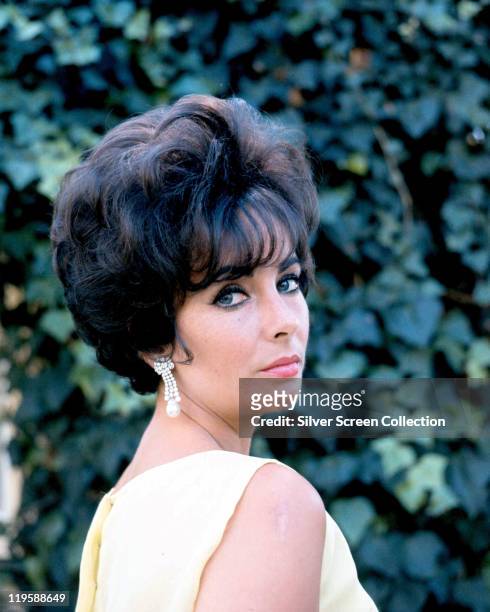 Elizabeth Taylor , British actress, looking over her shoulder, against a background of ivy leaves, circa 1960.