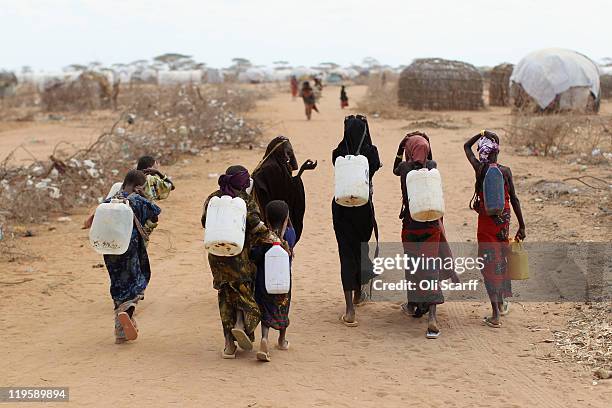 Somalian refugees return from collecting water at the edge of the Dagahaley refugee camp which makes up part of the giant Dadaab refugee settlement...