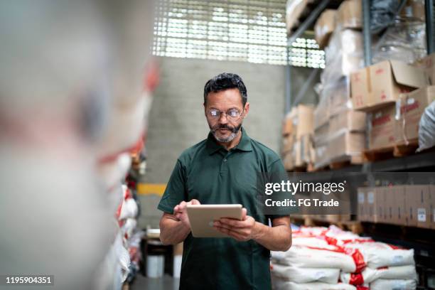 manager met behulp van zijn tablet werken in magazijn/industrie - data storage stockfoto's en -beelden