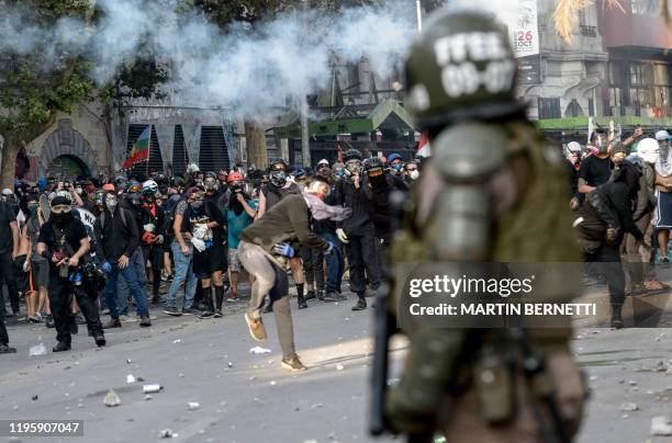 Demonstrators clash with riot police during a protest against the government of President Sebastian Pinera, in Santiago, on January 24, 2020. -...