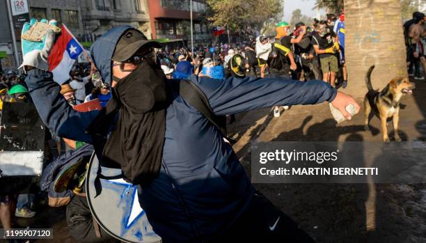 Demonstrator aims a stone at riot police during clashes which erupted during a protest against the government of President Sebastian Pinera, in...