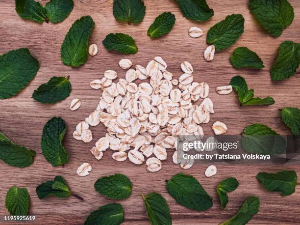 oat flakes and mint leaves on wooden table flat lay background - haferflocken stock-fotos und bilder