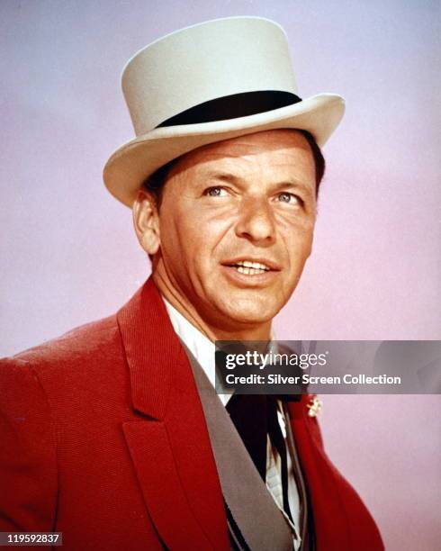 Frank Sinatra , US singer and actor, wearing a white top hat, with a black band, white shirt, grey wasitcoat, red jacket and a black western tie in a...