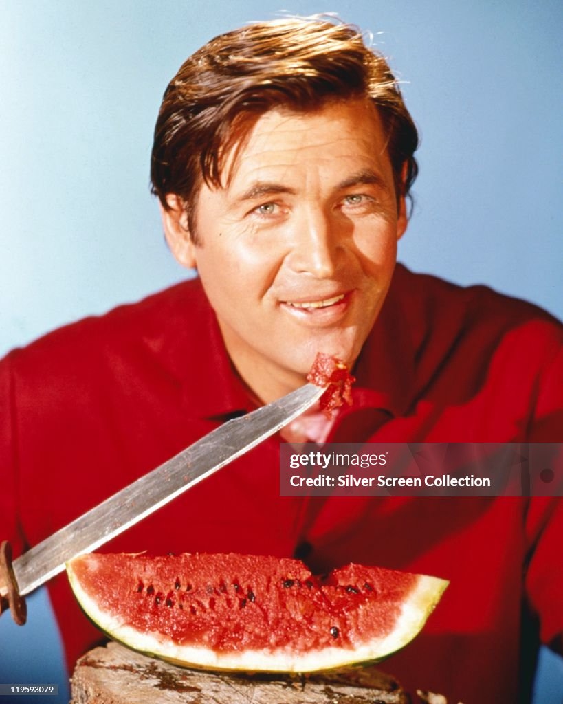 Fess Parker , US actor, wearing a red shirt while posing with a large