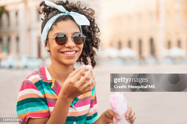 teen girl eating cotton candy outdoors - 12 13 girls stock pictures, royalty-free photos & images