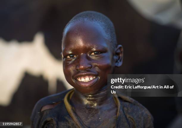 Smiling Mundari tribe boy after showering in the cow urine to dye his hair in orange, Central Equatoria, Terekeka, South Sudan on November 27, 2019...