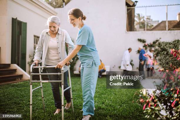 infermiera donna che aiuta donna anziana con mobility walker in casa di cura - infermiera foto e immagini stock