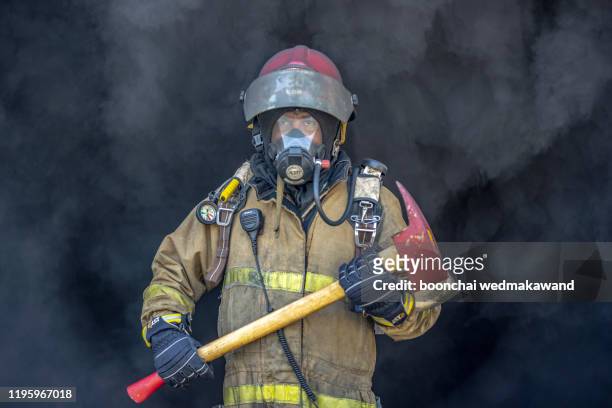 rescue firefighter in safe helmet and uniform over grey background. - fireman axe stock pictures, royalty-free photos & images